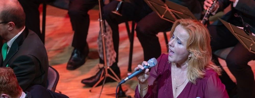 Markéta Amerighi zpívá sólo na koncertě, bordó šaty